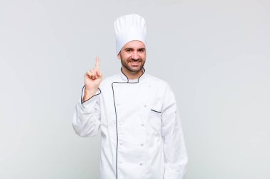 Kel adam neşeyle ve mutlulukla gülümsüyor, tek eliyle yukarıyı göstererek boşluğu kopyalıyor.