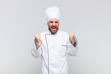 Kel adam mutlu, şaşırmış ve gururlu, bağırıyor ve başarıyı büyük bir gülümsemeyle kutluyor.