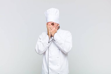 Kel bir adam korkmuş ya da utanmış hisseder. Gözleri yarı kapalı bir şekilde dikizler ya da gözetler.