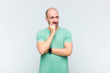 Şaşırmış, gergin, endişeli ya da korkmuş bakışları olan kel bir adam kopya uzayına bakıyor.