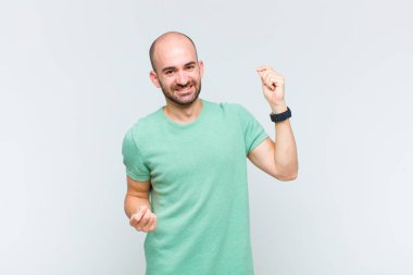 Kel adam gülümsüyor, kaygısız hissediyor, rahat ve mutlu, dans ediyor ve müzik dinliyor, bir partide eğleniyor.