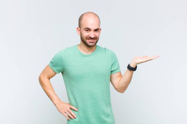 Kel adam gülümsüyor, kendinden emin, başarılı ve mutlu hissediyor, fotokopi alanında fikir veya konsept gösteriyor.