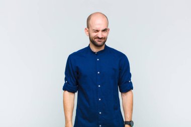 Kel adam mutlu ve arkadaş canlısı görünüyor, gülümsüyor ve sana olumlu bir tavırla göz kırpıyor.