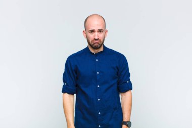 Kel bir adam üzgün ve mızmızlanıyor. Mutsuz bir bakışla, olumsuz ve hayal kırıklığına uğramış bir tavırla ağlıyor.