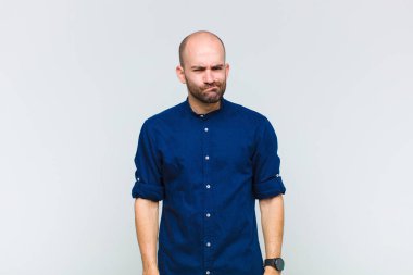 Kafası karışık ve şüpheli hisseden kel bir adam merak ediyor ya da karar vermeye çalışıyor.