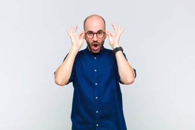 Kel adam şaşkın, şaşırmış ve şaşırmış hissediyor. Elinde şaşkın, inançsız bir bakışla gözlük tutuyor.