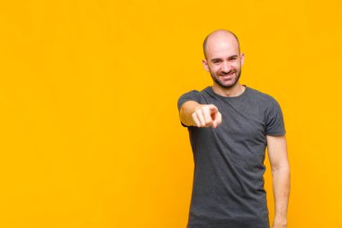 Kel adam kameraya bakıyor, tatmin olmuş, kendinden emin, dostane bir gülümsemeyle, seni seçiyor.