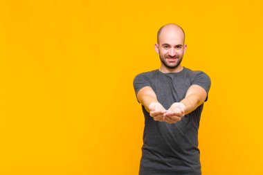 Dost canlısı, kendine güvenen, olumlu bakışlı, bir nesne ya da konsept sunan ve gösteren kel bir adam.