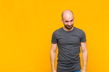 Kel adam gururlu, kendinden emin, havalı, küstah ve küstah görünüyor, gülümsüyor, başarılı hissediyor.