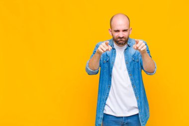 Kel adam kamerayı iki parmağıyla ve kızgın bir ifadeyle sana görevini yapmanı söylüyor.