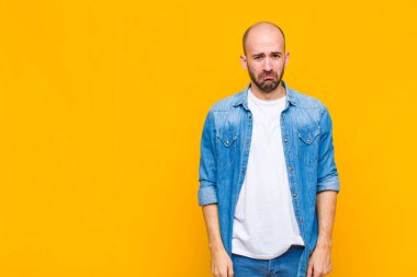 Kel bir adam üzgün ve mızmızlanıyor. Mutsuz bir bakışla, olumsuz ve hayal kırıklığına uğramış bir tavırla ağlıyor.