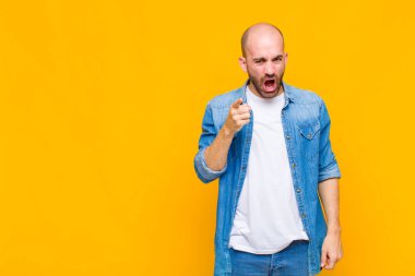 Kızgın agresif bir ifadeyle kameraya bakan kel bir adam kızgın, çılgın bir patron gibi görünüyor.