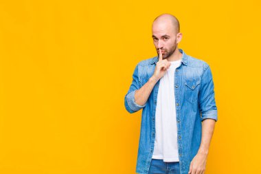 Kel adam sessizlik ve sessizlik istiyor, parmağıyla ağzının önünde işaret ediyor, 