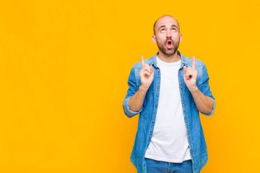 Kel adam korkuyla ve ağzı açık bir şekilde şaşkın ve şaşkın bir bakışla yukarıya bakıyor.