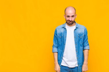 Kafası karışmış, kafası karışmış, sinirsel bir hareketle dudağını ısıran, sorunun cevabını bilmeyen kel bir adam.