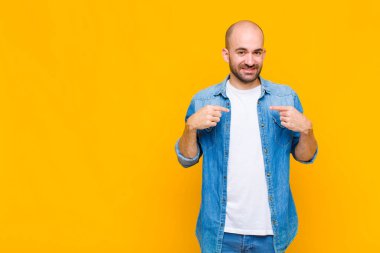 Kel adam gururlu, pozitif ve iki eliyle göğsünü gösteren