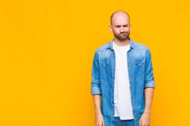 Kafası karışık ve şüpheli hisseden kel bir adam merak ediyor ya da karar vermeye çalışıyor.