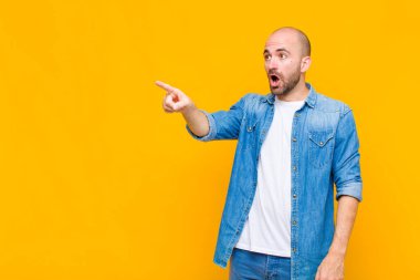 Kel adam şaşkın ve şaşırmış hissediyor, hayranlıkla yukarı bakıyor, şaşırmış, ağzı açık bakıyor.