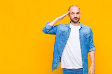 Kel adam kameraya askeri bir selamlama ile selam veriyor. Şeref ve vatanseverlik adına. Saygı gösteriyor.