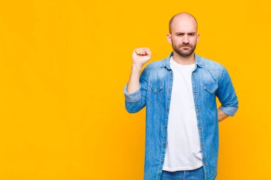 Kel adam ciddi, güçlü ve asi hissediyor, yumruğunu kaldırıyor, protesto ediyor ya da devrim için savaşıyor.