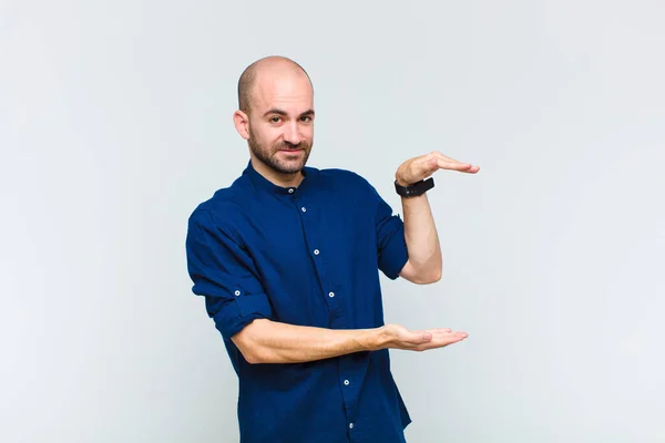 Φαλακρός Άνθρωπος Κρατώντας Ένα Αντικείμενο Δύο Χέρια Στο Πλαϊνό Χώρο — Φωτογραφία Αρχείου