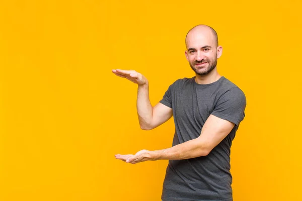 Uomo Calvo Sorridente Sentirsi Felice Positivo Soddisfatto Tenendo Mostrando Oggetto — Foto Stock