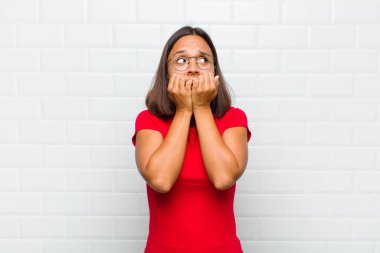 Latin kadın endişeli, gergin, stresli ve korkmuş görünüyor, tırnaklarını yiyor ve yanal fotokopi için yer arıyor.