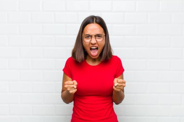 Sinirli, hayal kırıklığına uğramış, kızgın bakışlar ve sıkı yumruklarla bağıran Latin bir kadın.