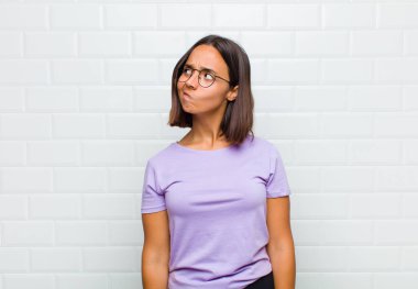 Şaşırmış ve kafası karışmış görünen Latin bir kadın, bir sorunu çözmeye çalışıyor ya da düşünüyor.