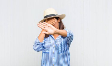 Latin kadın yüzünü eliyle kapatıyor ve kamerayı durdurmak için diğer elini öne koyuyor, fotoğraf ya da resimleri reddediyor.