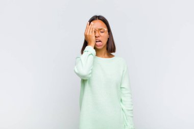 Latin bir kadın uykulu, sıkılmış ve esniyor, baş ağrısı ve yüzünün yarısını kaplayan bir elle.