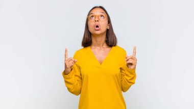 Latin kadın korkuyla ve ağzı açık bir şekilde şaşkın ve şaşkın bir bakışla yukarıya bakıyor.