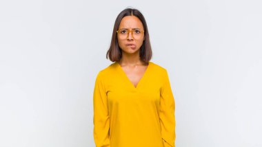 Şaşırmış ve kafası karışmış görünen Latin bir kadın. Sinirli bir hareketle dudağını ısırıyor. Sorunun cevabını bilmiyor.