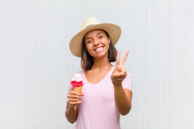 Genç İspanyol kadın gülümsüyor ve mutlu görünüyor, kaygısız ve pozitif, zafer ya da barışı simgeliyor.