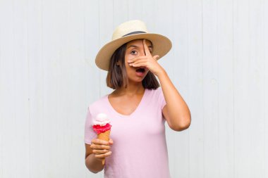 Genç İspanyol kadın şok olmuş, korkmuş ya da korkmuş görünüyor. Yüzü elle kaplanmış ve parmaklarının arasından gizlice bakıyor.