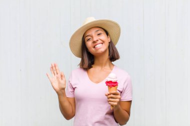 Genç İspanyol kadın mutlu ve neşeyle gülümsüyor, el sallıyor, sizi selamlıyor ya da veda ediyor.