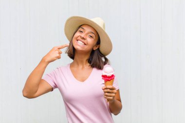 Genç İspanyol kadın kendine güvenerek gülümsüyor. Geniş gülümseme, pozitif, rahat, tatmin olmuş tavır.