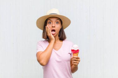 Genç İspanyol kadın şok olmuş ve korkmuş hissediyor, ağzı açık ve elleri yanaklarında korkmuş görünüyor.