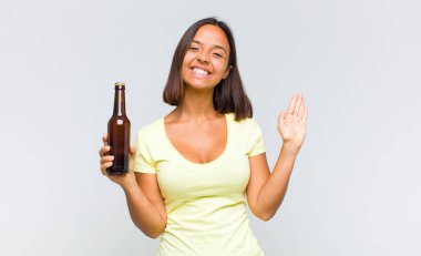 Genç İspanyol kadın mutlu ve neşeyle gülümsüyor, el sallıyor, sizi selamlıyor ya da veda ediyor.