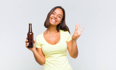 Genç İspanyol kadın gülümsüyor ve arkadaş canlısı görünüyor. Üç ya da üç numarayı gösteriyor. Elleri önde, geri sayıyor.