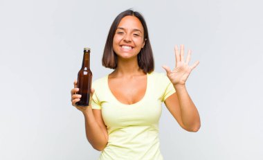 Genç İspanyol kadın gülümsüyor ve arkadaş canlısı görünüyor, 5 ya da 5 numarayı gösteriyor, elleri önde, geriye doğru sayıyor