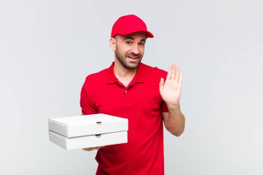 Genç kel adam mutlu ve neşeyle gülümsüyor, el sallıyor, seni selamlıyor ve selamlıyor, ya da elveda diyor.