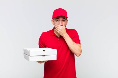 Genç kel adam elleri ile ağzını kapatıyor, şok olmuş, şaşırmış bir ifadeyle, bir sır saklıyor ya da 