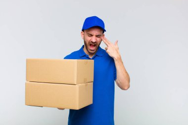 Genç kel adam mutsuz ve stresli görünüyor, intihar jesti elle silah işareti yapıyor, kafasını işaret ediyor.