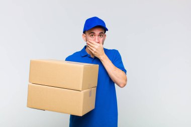 Genç kel adam elleri ile ağzını kapatıyor, şok olmuş, şaşırmış bir ifadeyle, bir sır saklıyor ya da 