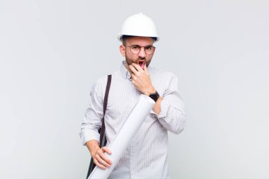 Genç kel bir adam ağzı ve gözleri sonuna kadar açık ve eli çenesinde, nahoş bir şekilde şokta, ne söylüyor ya da vay canına