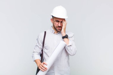 Genç kel adam yorgun, sıkıcı ve sıkıcı bir işin ardından sıkılmış, hayal kırıklığına uğramış ve uykulu hissediyor.