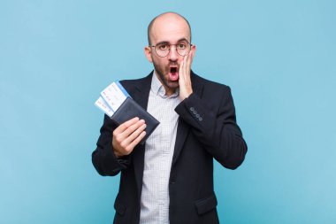 Genç kel adam şok olmuş ve korkmuş hissediyor, ağzı açık ve elleri yanaklarında korkmuş görünüyor.