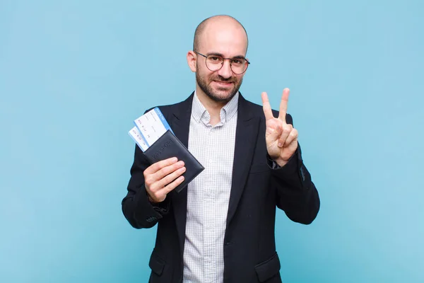 young bald man smiling and looking friendly, showing number two or second with hand forward, counting down