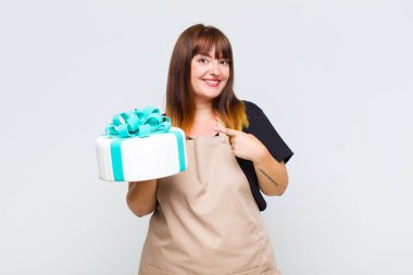 Artı boyut olarak gülümseyen, mutlu hisseden, kenarı ve yukarıyı gösteren, kopya uzayda nesneler gösteren bir kadın.